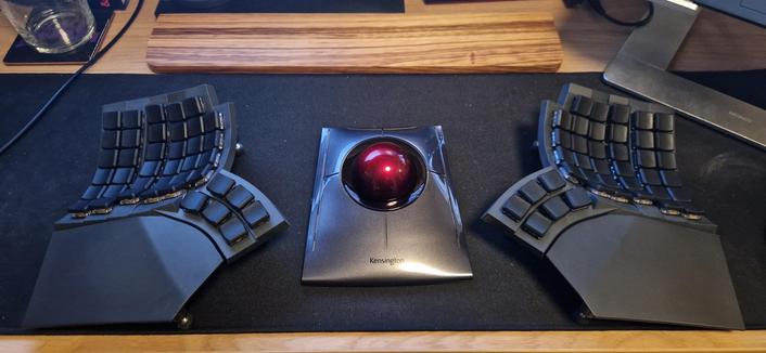A Kensington SlimBlade ergonomic mouse/trackball sits between the two halves of a Glove80 split keyboard on my desk
