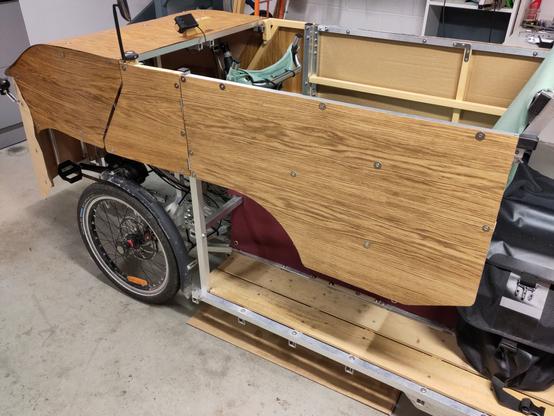 Photo du vhéliotech modifié, porte fermée. On voit donc le côté extérieur, qui est lisse et présente des motifs de bois (puisque c'est du placage bois, c'est à dire une feuille de bois de moins d'un millimètre d'épaisseur). Une dizaine de vis maintiennent le placage bois sur la structure, avec des rondelles pour répartir la pression sur une surface de bois plus large.