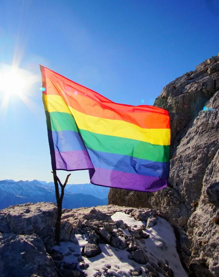 Regenbogenfahne auf einem Felsen am Berg