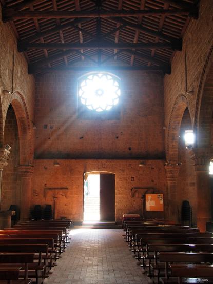 Blick vom Altar aus durch die Kirche San Marco vom 13. bis 14. Jahrhundert in einfachem romanischem Stil zur sonnenbestrahlten Rosette über dem Eingang.