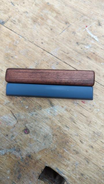 An image showing a comparison between a wooden keycap and the original keycap