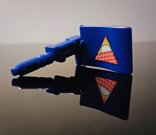 The Flag weapon by itself, flag piece aligned 90 degrees around to show off that glorious logo which, I now realise, is a classic original representation of the what we now call 80s RetroSynthWave, a sun rising over a flat grid plane, here angled up right. Gobots, retro-cool before retro was even a thing.