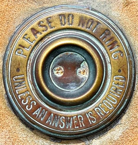 An old brass door bell with the following inscribed around it: Please Do Not Ring Unless An Answer Is Required.