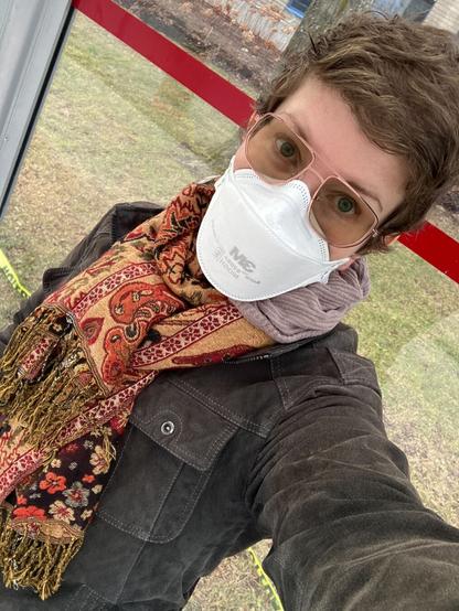 Selfie of a middle aged white woman in a respirator at a bus stop
