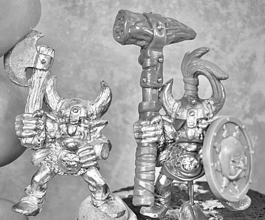 A metal goblin armed with an axe next to a conversion using the same model. Wears a meteoric iron hammer, a fur ponytail , an evil sun shield and an eyepatch. Also has a bigger belly.