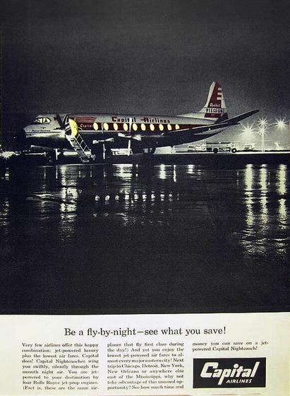 A prop plane parks outside under wet dark conditions.