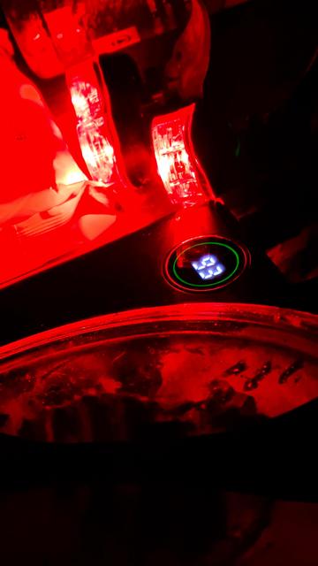 Close up of a cluttered tent floor. Stark red light from charging bicycle lights. A power bank with round display says 93.