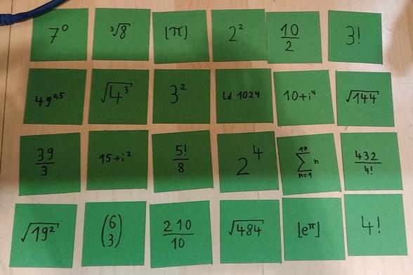 24 green square pieces of paper. There is a mathematical term on each piece, that equals to one of the numbers from 1 to 24. For example 4! on the last one.