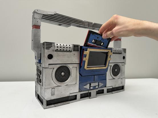 SoundWave in his boombox mode with a cassette tape being loaded in.