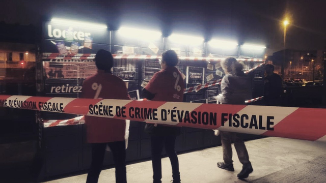 Des militant·es recouvrent un locker noir de banderoles et autocollants