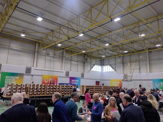 A photo of people watching the count taking place in a large hall