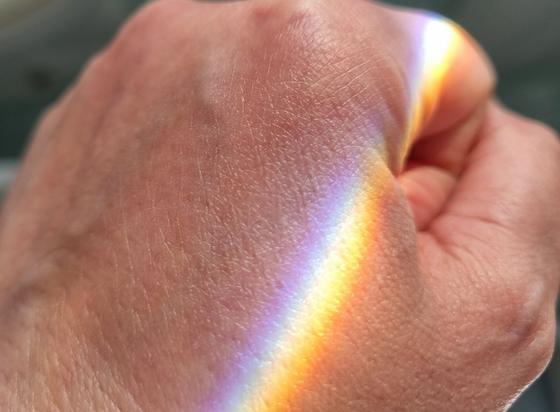 Spettro di luce arcobaleno che si posa sul dorso della mano