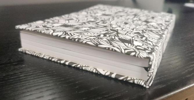 a book with a pattern of black and white leaves. View from top side with detail on the spine