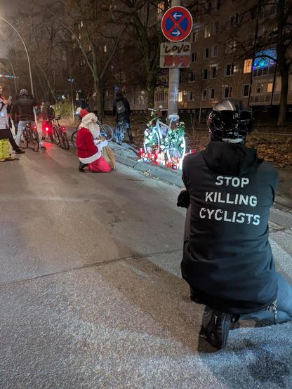 Das Bild zeigt die Unfallstelle an der Landsberger Allee in Berlin, an der ein 38 jähriger Radfahrer Anfang der Woche motorisierter Gewalt zum Opfer gefallen ist. Im Vordergrund kniet eine Person, deren Jacke die Aufschrift "Stop killing cyclists!" trägt. Im Zentrum ist ein weißes Ghostbike zu sehen, das mit weißen Rosen und Grabkerzen geschmückt ist. Das Ghostbike ist an einer Straßenlaterne angelehnt, an der ein Schild angebracht wurde, das die Aufschrift  "Love" und drei Herzen trägt.

Direkt vor dem Ghostbike kniet eine weitere Person, um dem Radfahrer die letzte Ehre zu erweisen. Im Hintergrund sind weitere Radfahrer zu sehen. Es ist abends.