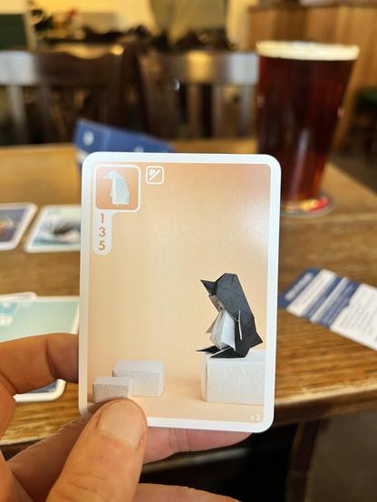A penguin card in Sea Salt and Paper. A pint of beer bitter in the background.