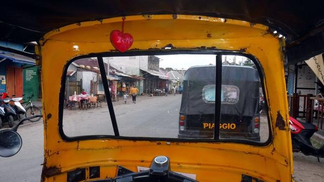 Photo looking through the windscreen of a Tuktuk 3-wheeler taxi, parked, no driver apparent.