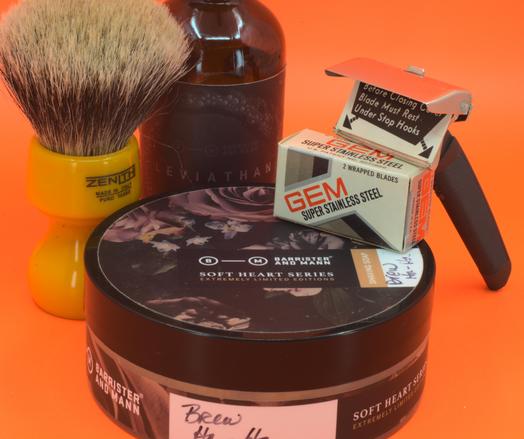 An open GEM Contour II leaning on a tub of BaM Brew Ha-Ha next to a bottle of BaM Leviathan balm and a beautiful butterscotch Zenith badger brush