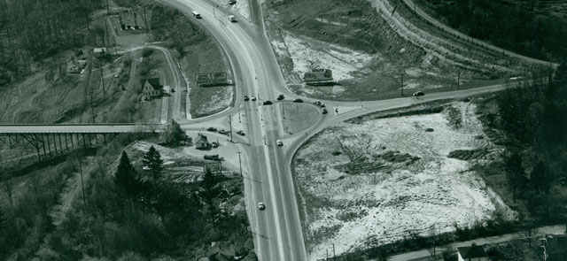 old black-and-white aerial view, facing west, most of the area around the intersection is cleared lots, there's no car wash, i-5 has not been built yet (in the ditch on the left)  The old wooden bridge takes Terwilliger over the ditch.