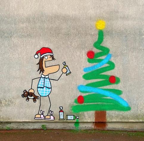 Streetartwall. A small cartoon figure, spray-painted with simple lines, has drawn a Christmas tree on a gray wall. The little man is wearing a red Christmas hat, short blue and white checked pyjamas and pink slippers. He is holding a teddy bear in one hand and a spray can in the other, with which he has sprayed a Christmas tree with a green wave, a brown line and a few red dots. He hasn't even forgotten the star.
Info: The anonymous artist "TocToc" is a French freelance illustrator and video artist. He exhibits his work in galleries around the world. In 2012, he created the simple figure DUDUSS when he was  an art student and still sprays it on the walls of cities today.