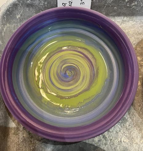 Shallow bowl made on a pottery wheel under glazed in green to blue to purple on the rim. Second smaller dipping bowl under glazed in red