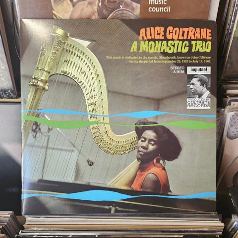 Album cover features a color photograph of Alice Coltrane seated with a large golden harp, next to a piano. Blue and green wavy lines are superimposed across the image.