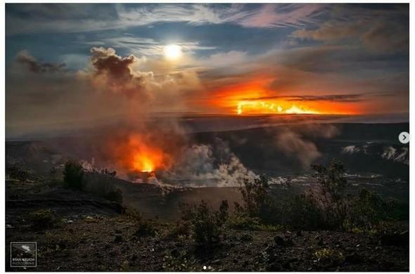 A vibrant picture of two erupting volcanoes a full moon and bright clouds.