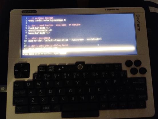 photo showing the DevTerm running Emacs in full screen cool-retro-term in amber color scheme