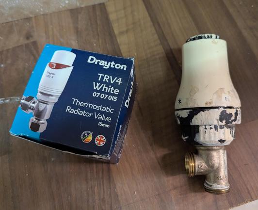 The old thermostatic radiator valve on the right of the image, sullied with paint from sloppy decorating in the past. The new TRV still in the box on the left of the picture.