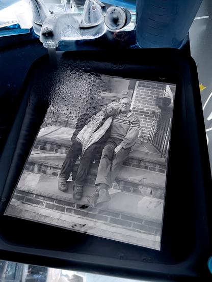 An inverted cell phone photo of a paper negative in the wash. The negative looks like a positive but the sink and background all look weird because they are inverted.