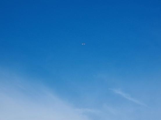 In lontananza si vede un aereo in decollo che attraversa il cielo blu