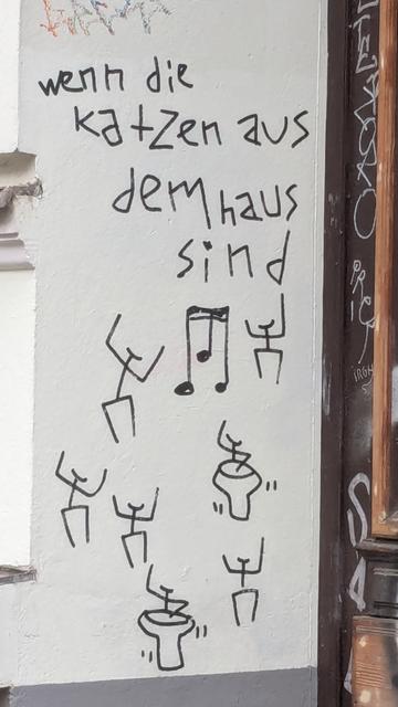 An die Hauswand Gesprühtes:

"wenn die katzen aus dem haus sind" in aus wenigen Strichen bestehenden Lettern, darunter eine Musiknote (16tel Triole) und darum tanzende Strichmännchen:Weibchen und "Strich-Drummer:innen".
Dada-Appeal.