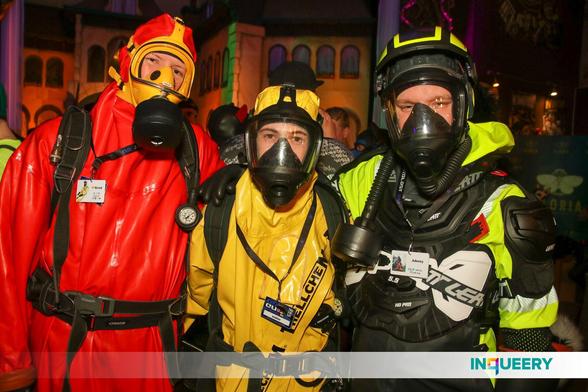 The fox, Exodiver and Adensy (from left to right) stand next to each other, with the fox and Adensy resting their hans on the shoulders of Exodiver and Exodiver holding his hands on the backs of the fox and Adensy. All three are facing the camera. The fox wears his red Pflüger hazmat suit, full SCBA set and a yellow gas mask with filter. Exodiver wears his yellow Trellchem Super hazmat suit with full SCBA set and a black gas mask. Adensy wears neon yellow-black raingear with a Leatt MX protector, Lineman rubber gloves and a black gas mask with hose and filter attached, and a neon yellow-black helmet on top.