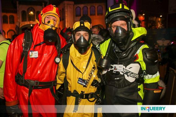 The fox, Exodiver and Adensy (from left to right) stand next to each other, with the fox and Adensy resting their hans on the shoulders of Exodiver and Exodiver holding his hands on the backs of the fox and Adensy. All three are facing the camera. The fox wears his red Pflüger hazmat suit, full SCBA set and a yellow gas mask with filter. Exodiver wears his yellow Trellchem Super hazmat suit with full SCBA set and a black gas mask. Adensy wears neon yellow-black raingear with a Leatt MX protector, Lineman rubber gloves and a black gas mask with hose and filter attached, and a neon yellow-black helmet on top.