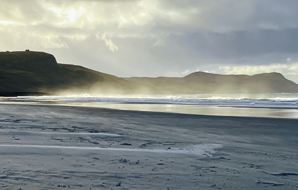 Beach with spray blown up off the sea