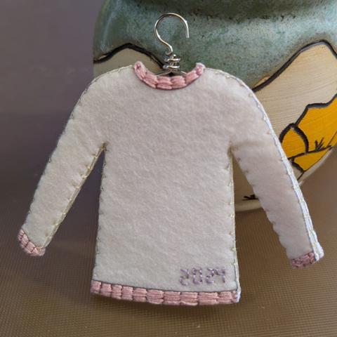 A small Christmas ornament style embroidered felt sweater with the year stitched on the back.