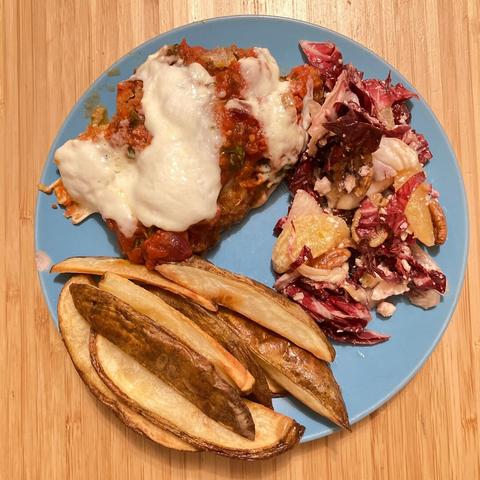Chicken parm served with a salad and home fries.