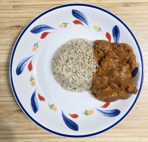 A thick peanut butter and tomato stew with chicken, served with rice.