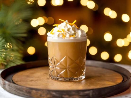 Nutcracker cocktail with whipped cream and orange zest on topa
