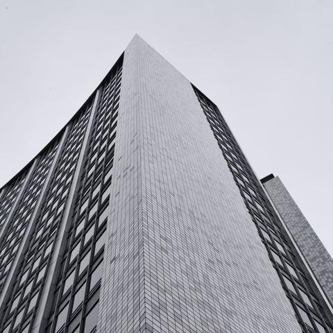 Photograph looking up at the old AMP building in Sydney.  The building is a tower of steel, glass and white/grey tiles against a monotone grey sky.