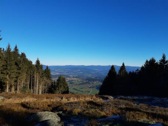 Blick vom Pröller auf Bayerwaldgipfel, u.a. Großer Arber. Blauer Himmel, rechts und links Fichten