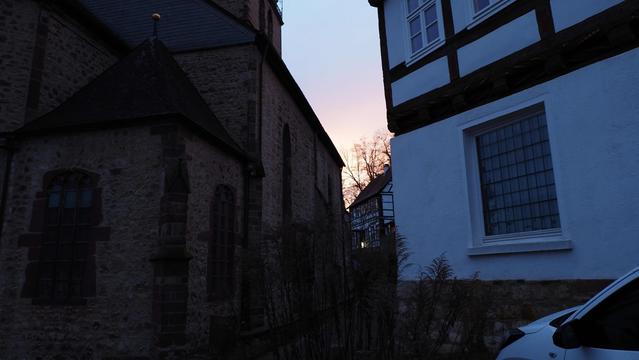 Gasse zwischen Kirche und Fachwerkhäusern. Zartes Rosa am Himmel
