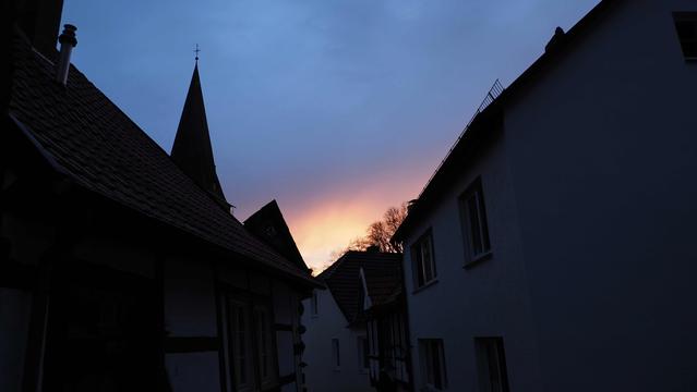 Gasse, Fachwerkhäuser und ein Kirchturm. Himel grau ins rötliche übergehend!