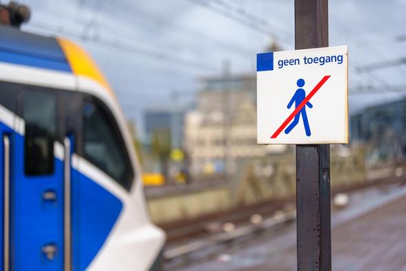 Train on the platform with a sign next to it.