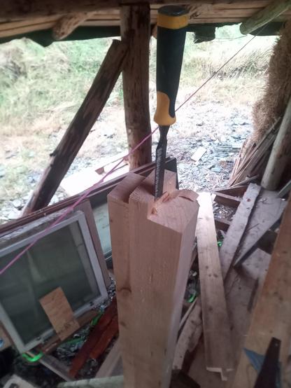 Making a quick edit to the tenon on the top of the right hand door post, with the door post already fitted in its final position... Because the mortice was not quite wide enough!

In the background you can see timbers and spare windows in what will become an outdoor decking area.