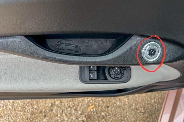 The driver’s door on a 2024 Fiat 500e. The button to open the door is circled.