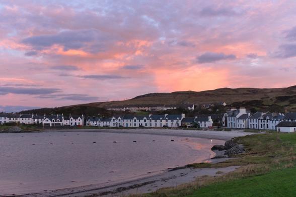 pink, cloudy sunrise over a village around a bay