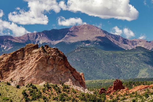 Garden Of The Gods and Pikes Peak

This is an image of The Garden Of The Gods with Pike's Peak serving as a backdrop. This is located just outside of Colorado Springs, Colorado.
Garden Of The Gods is an area with some amazing rock formations that appear to have risen from the ground in the surrounding area. The formations are a reddish/brown color that rise above the surrounding landscape consisting of small bushes and grass.
Pike's Peak rises up in the background. The peak is above the tree line exposing the purple tinted rock.