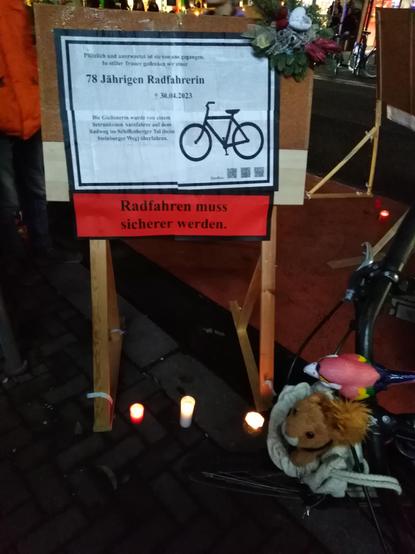 Standschild auf Ladezonenparkplatz: Rechts ist am Schild ein Trauergesteck angebracht, unterhalb stehen Grabkerzen.
Rechtsbündig auf dem Trauerschild ist ein Radsymbol abgebildet. Linksbündig stehen folgende Zeilen:
"Plötzlich und unerwartet ist sie von uns gegangen. In stiller Trauer gedenken wir einer 
[hervorgehoben] 78 Jährigen Radfahrerin
[Kreuzsymbol] 30.04.2023

Die Gießenerin wurde von einem betrunkenen Autofahrer auf dem Radweg im Schiffenberger Tal (beim Steinberger Weg) überfahren."

Unterhalb der "Traueranzeige" steht ein im Zigarettenschachtelwarnungsstil, rot unterlegter Text: "Radfahren muss sicherer werden."
Puschel ist vor dem Schild am Radlenker im Transportbeutel abgebildet. Neben Puschel hockt der Quietschepapagei (Fahrradklingel) mit am Lenker.