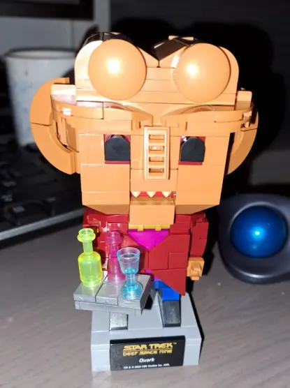 Quark made out of building bricks of the same format as Lego. Except this is BlueBrixx. 

This is a frontal picture of Quark in funko pop style. He's serving you a platter with some.. uh.. synthale? Or kanar? Who knows! He's got the lobes for this!

His head is like 50% of the construction, lol. There's a plaque on the bottom of the foundation reading Star Trek Deep Space Nine, Quark. And some copyright thingy in tiny font below.