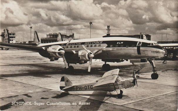 Sepia toned photo showing the Connie parked, and the service door is open. Next to it is a very small tricycle landing gear plane. Very little plane